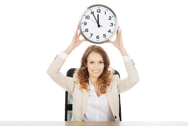 Photo portrait of businesswoman holding clock on chair against white background