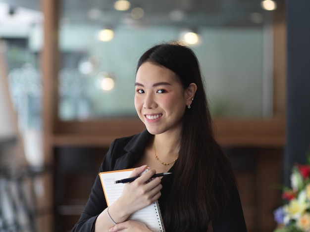 Portrait of businesswoman holding schedule book while standing in office room