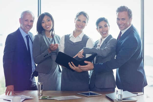 Portrait of businesswoman looking at organizer and interacting with team in office