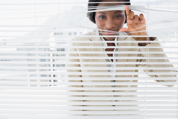 Photo portrait of a businesswoman peeking through blinds