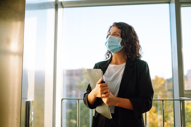 Portrait of businesswoman in protective face mask office\
manager back at work in office