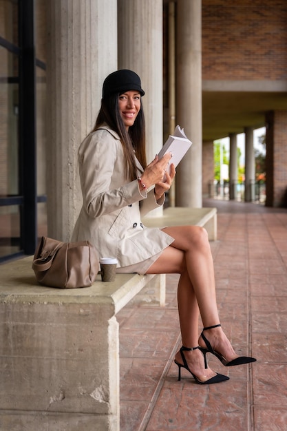 Portrait of a businesswoman reading a book outside the office copy space and cup of coffee