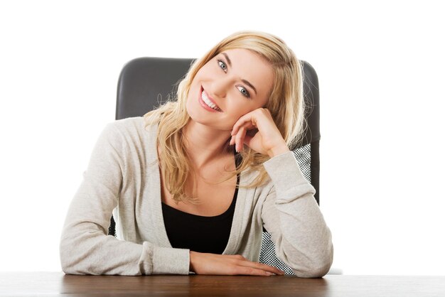 Portrait of businesswoman sitting at desk against white background