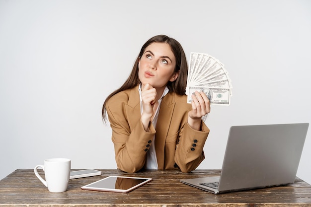 Portrait of businesswoman sitting in office with money working and making profit income posing happy...