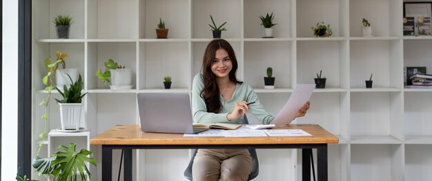 Portrait of businesswoman using laptop computer while working\
with using a calculator to calculate the numbers finance accounting\
concept banner shot