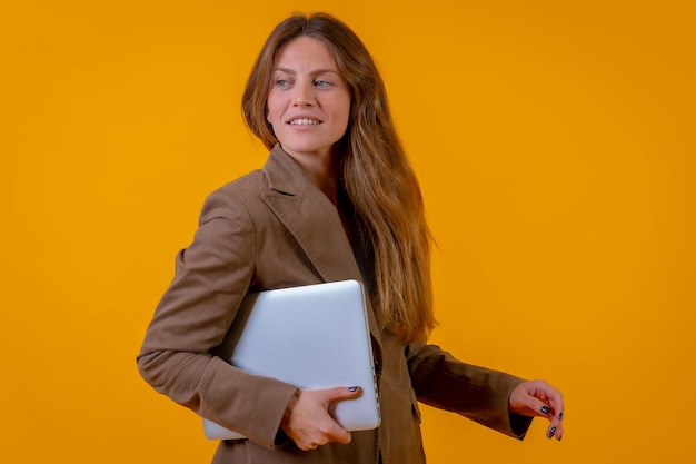 Portrait of a businesswoman with a computer or laptop on a yellow background young entrepreneur