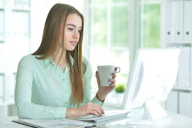 Photo portrait of businesswoman working in office and drinking coffee