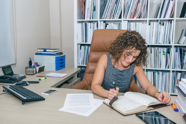 Foto ritratto di donna d'affari che scrive piani sul taccuino sul posto di lavoro