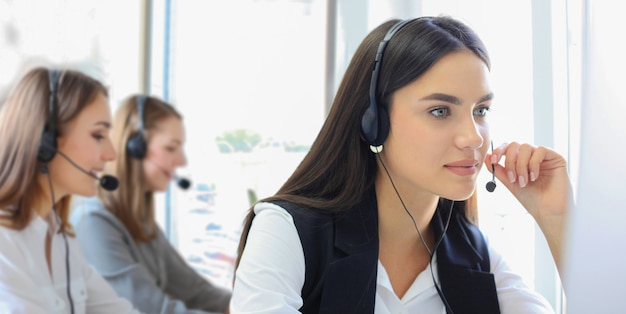 Portrait of call center worker accompanied by her team. Smiling customer support operator at work.