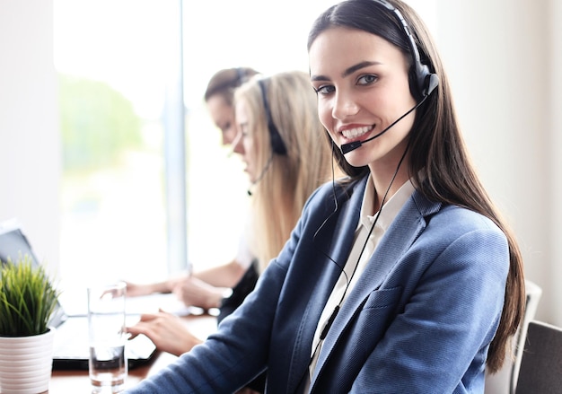 Портрет работника call-центра в сопровождении своей команды. Улыбающийся оператор службы поддержки клиентов на работе.