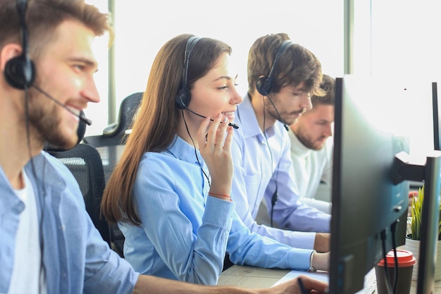 Portrait of call center worker accompanied by her team Smiling customer support operator at work