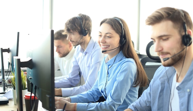 Portrait of call center worker accompanied by her team. Smiling customer support operator at work.