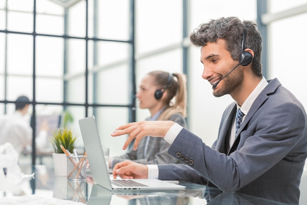 Portrait of call center worker accompanied by his team Smiling customer support operator at work