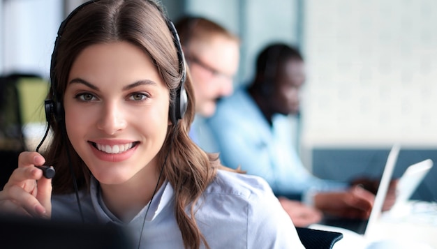 Portrait of call center worker accompanied by his team. Smiling customer support operator at work.