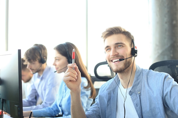 Portrait of call center worker accompanied by his team. Smiling customer support operator at work.