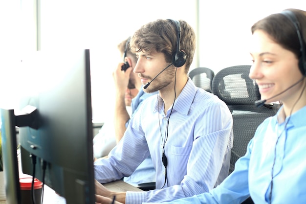 Portrait of call center worker accompanied by his team. Smiling customer support operator at work.