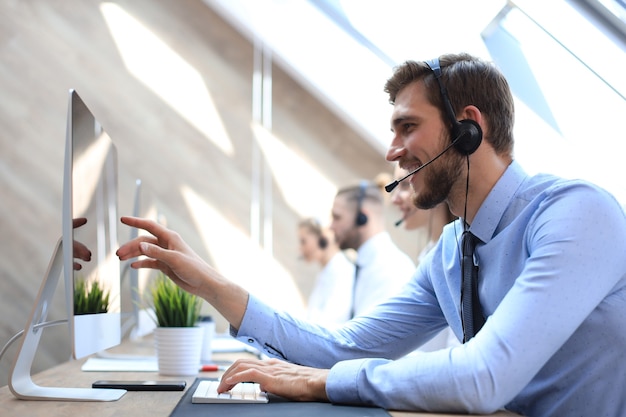 Portrait of call center worker accompanied by his team. Smiling customer support operator at work.