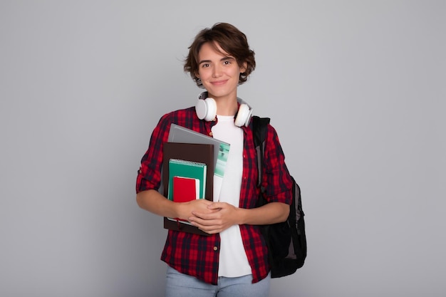 Photo portrait of a calm and confident modern female student with a backpack notebooks and books in her hands looking at the camera university study school education college classes study knowledge