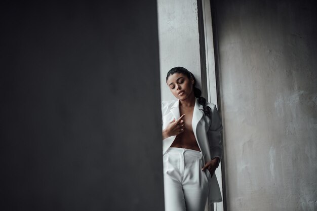 Portrait of candid authentic elegant sexy mixed race model girl posing in white pantsuit with bra