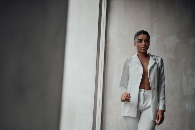 Portrait of candid authentic elegant sexy mixed race model girl posing in white pantsuit with bra