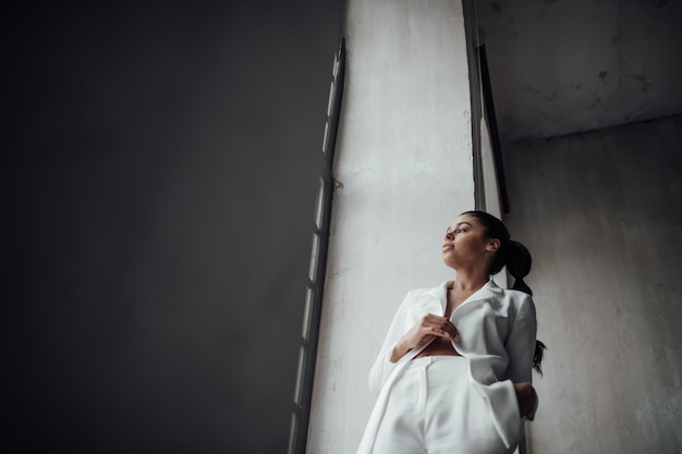 portrait of candid authentic elegant sexy mixed race model girl posing in white pantsuit with bra
