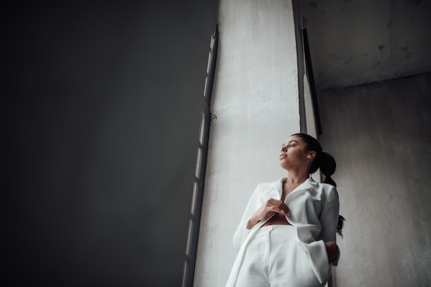 Portrait of candid authentic elegant sexy mixed race model girl posing in white pantsuit with bra