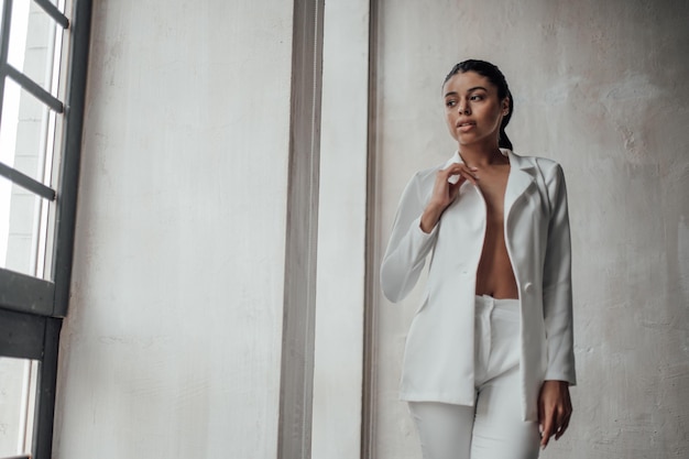 Photo portrait of candid authentic elegant sexy mixed race model girl posing in white pantsuit with bra