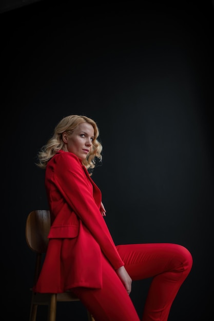 Portrait of candid authentic elegant sexy model blonde girl posing in bra and red pantsuit at studio