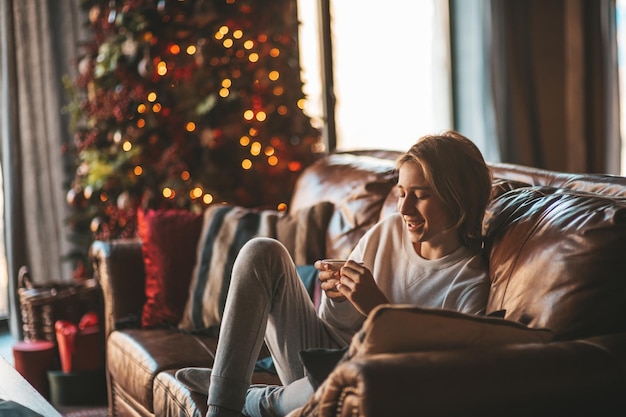 Portrait of candid authentic smiling boy teenager having fun emotion at wooden lodge Xmas decorated