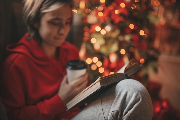 Photo portrait of candid authentic smiling boy teenager reading book on distance studying at home xmas