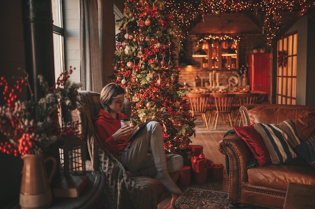 Portrait of candid authentic smiling boy teenager reading book on distance studying at home Xmas