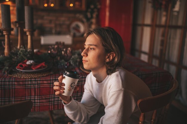 Foto ritratto di un autentico ragazzo adolescente sorridente che usa il telefono cellulare all'interno della casa di natale