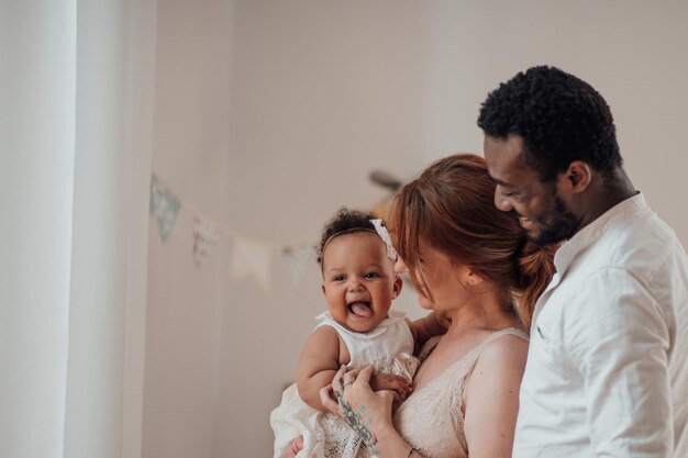 Photo portrait of candid friendly happy interracial family with swarthy baby together at children room