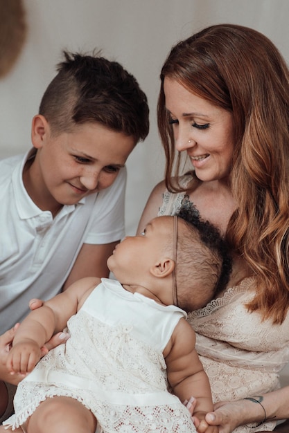 Foto ritratto di una famiglia interrazziale felice e amichevole con due bambini che trascorrono del tempo insieme a casa