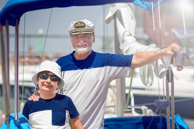 Portrait of the captain of a grandfather with his grandson on a yacht during a trip