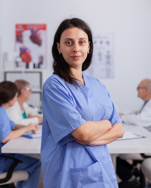 Portrait of cardiologist woman with stethoscope looking into front wearing medical uniform working in conference meeting room