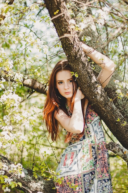 Portrait of carefree young woman in boho style dress in spring cherry blossom garden.