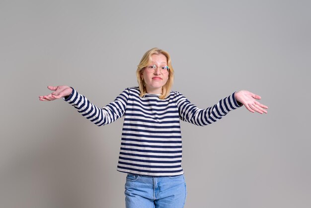 Portrait of careless businesswoman spreading hands and shrugging shoulders over white background