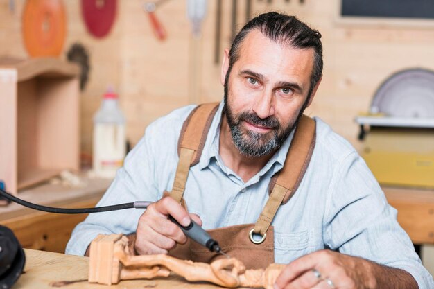 Photo portrait of carpenter carving on figurine in workshop