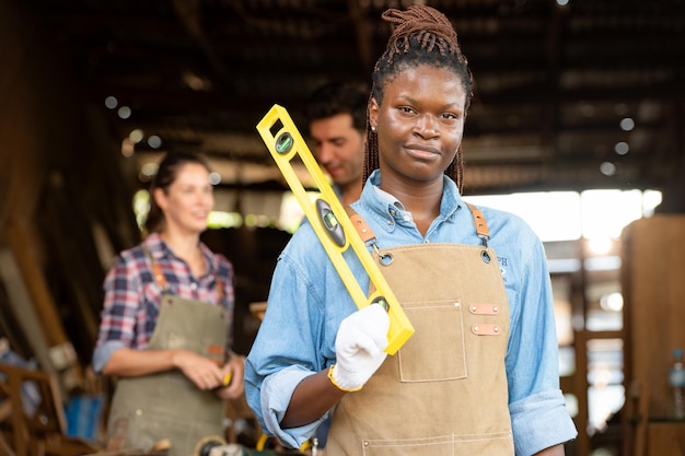 Portrait of carpenter female worker standing in front of colleague in workshop