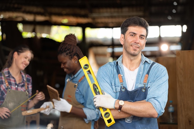 Portrait of carpenter male worker standing in front of colleague in workshop