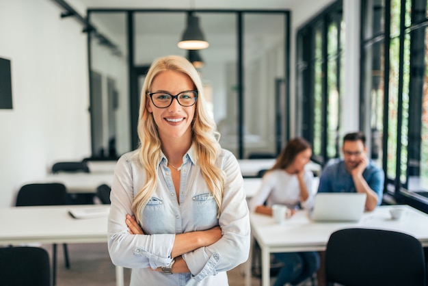 Portrait of casual female leader. Employees in the background.