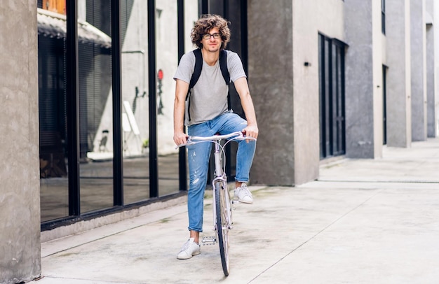 Ritratto di uomo d'affari bello hipster casual con zaino guardando la fotocamera durante il pendolarismo andare in bicicletta sulla strada della città andare al lavoro, viaggio d'affari, trasporto, concetto di bici