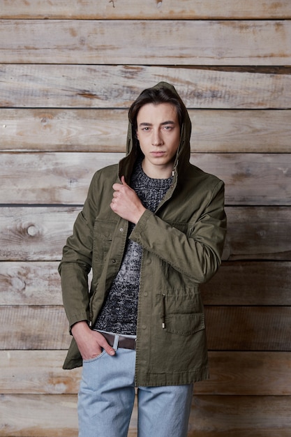 Portrait casual man in khaki jacket posing on wood wall