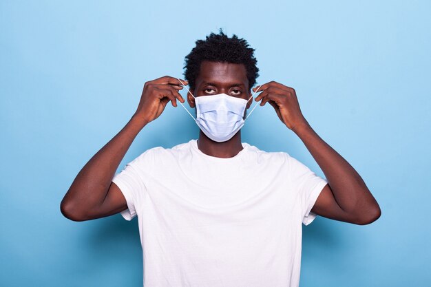 Portrait of casual man putting face mask on face for protection