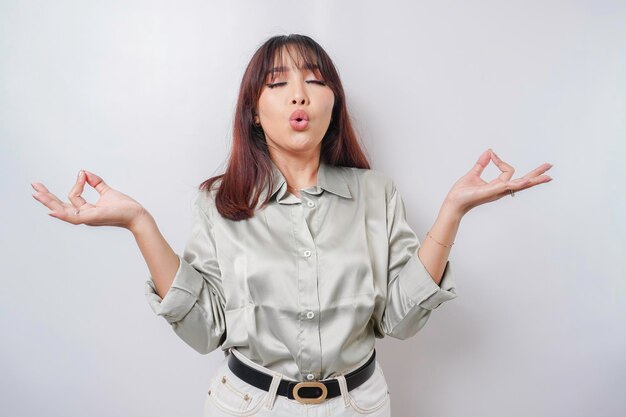 Portrait of a casual pretty woman meditating on white\
background stress free relief at work concept peaceful young woman\
practicing breathing yoga exercise