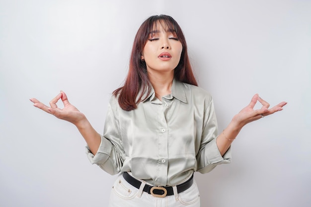 Portrait of a casual pretty woman meditating on white\
background stress free relief at work concept peaceful young woman\
practicing breathing yoga exercise