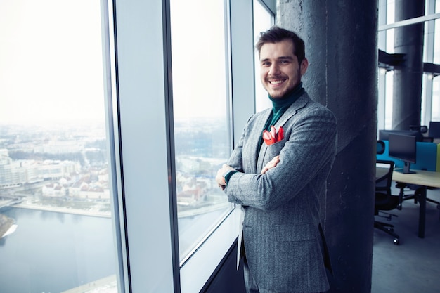 Portrait of a casually dressed young businessman standing in a trendy office.