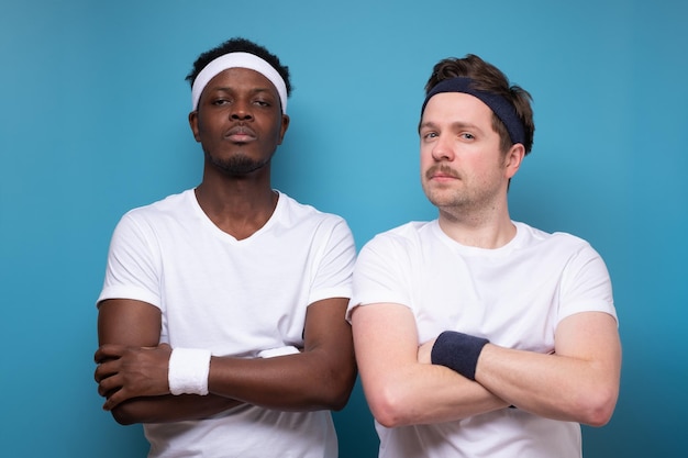 A portrait of a caucasian and african athletic men in a white tshirt serious crossed hands