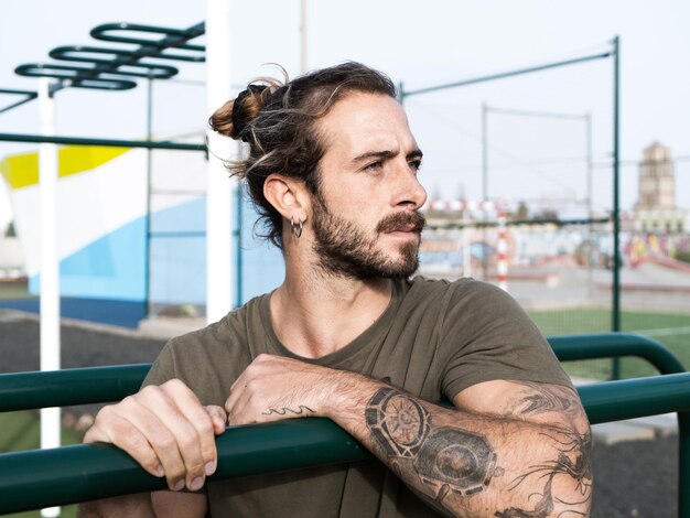 Photo portrait of a caucasian athlete man with long hair and beard outdoor at the calisthenics park